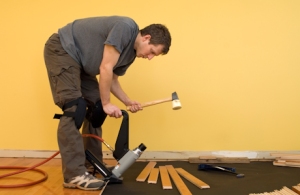 Man installing tongue and groove hardwood floor.